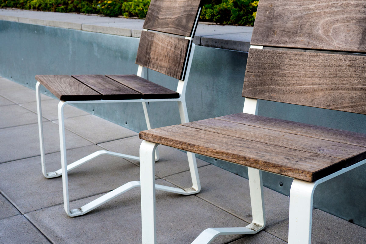Two wooden chairs on an outdoor tile patio beside a pool